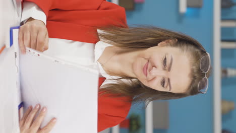 Vertical-video-of-Home-office-worker-woman-smiling-at-camera-looking-at-paperwork.